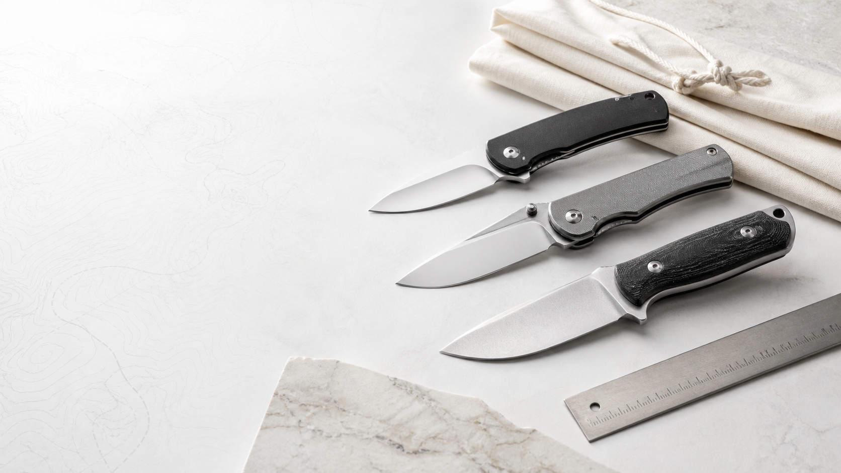 Outdoor knives arranged on a clean white surface